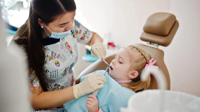 child receiving dental treatment at pediatric dentist clinic